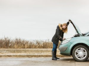 Blonde woman and broken down car on road